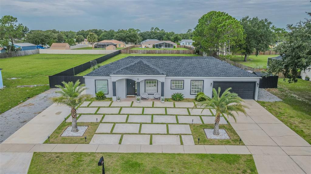 An aerial view shows a single-story house with a gray exterior, dark roof, and paved driveway — 12121 COLONIAL ESTATES LANE, RIVERVIEW, FL