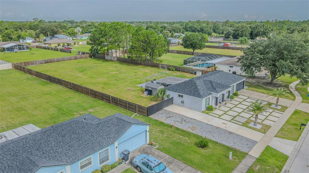 An aerial view shows a gray house with a grid-patterned concrete driveway and two palm trees — 12121 COLONIAL ESTATES LANE, RIVERVIEW, FL