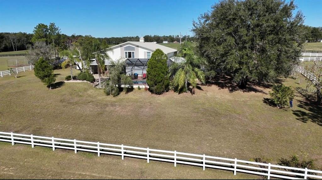 An aerial view shows a two-story house with a screened pool and white fencing — 17725 POWERLINE ROAD, DADE CITY, FL