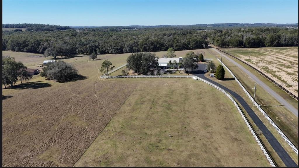 An aerial view shows a house surrounded by fenced pastures, trees, and a paved driveway — 17725 POWERLINE ROAD, DADE CITY, FL