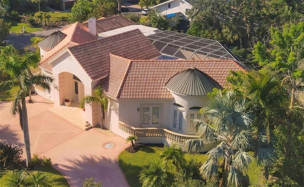 An aerial view of a suburban house with a light-colored tile roof and pool enclosure — 5331 SIESTA COVE DRIVE, SARASOTA, FL
