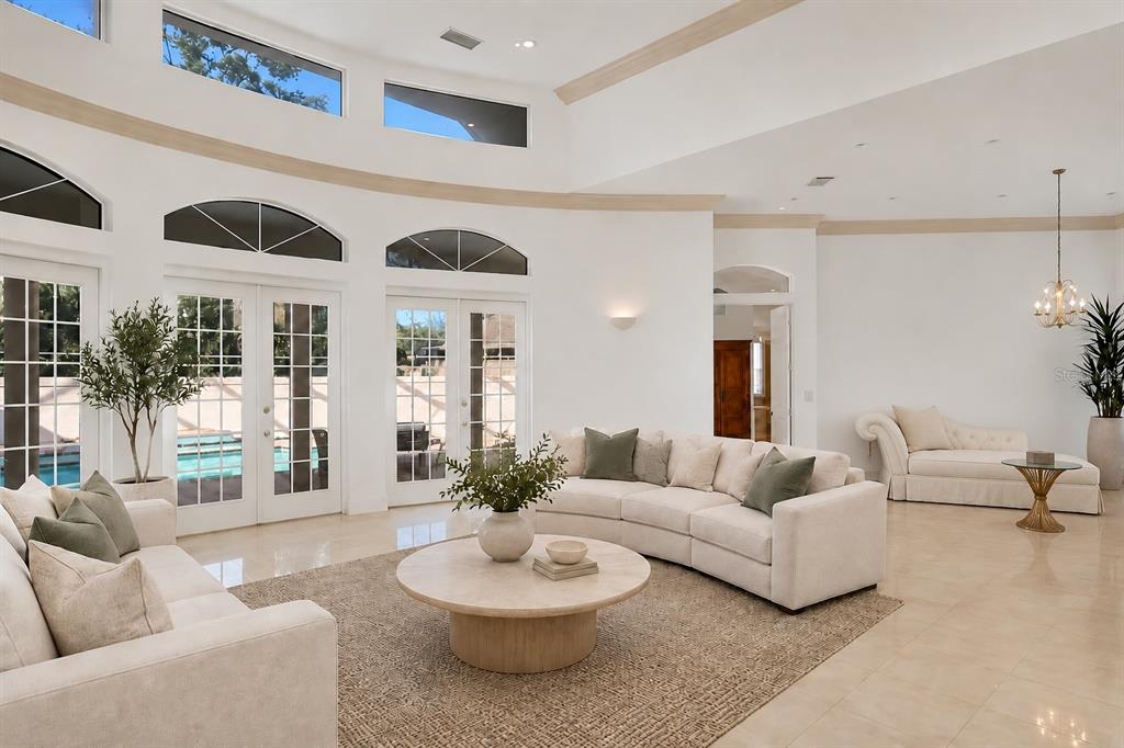 A spacious living room with high ceilings, white walls, tile floors, and large glass doors — 5331 SIESTA COVE DRIVE, SARASOTA, FL
