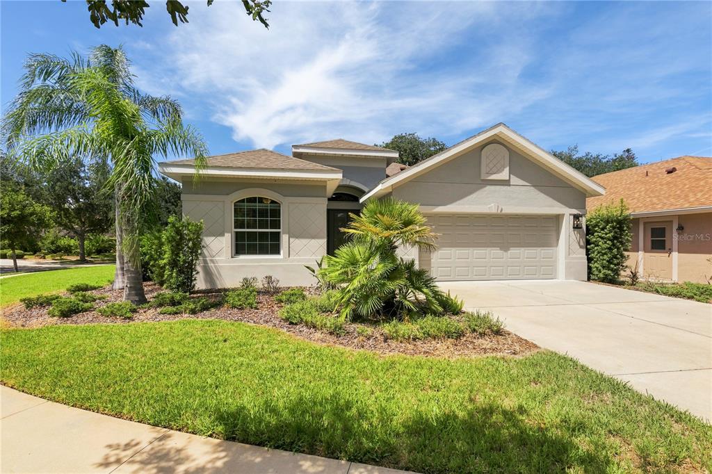A single-story house with a beige stucco exterior, a two-car garage, and a palm tree — 7 OASIS CIRCLE, PALM COAST, FL