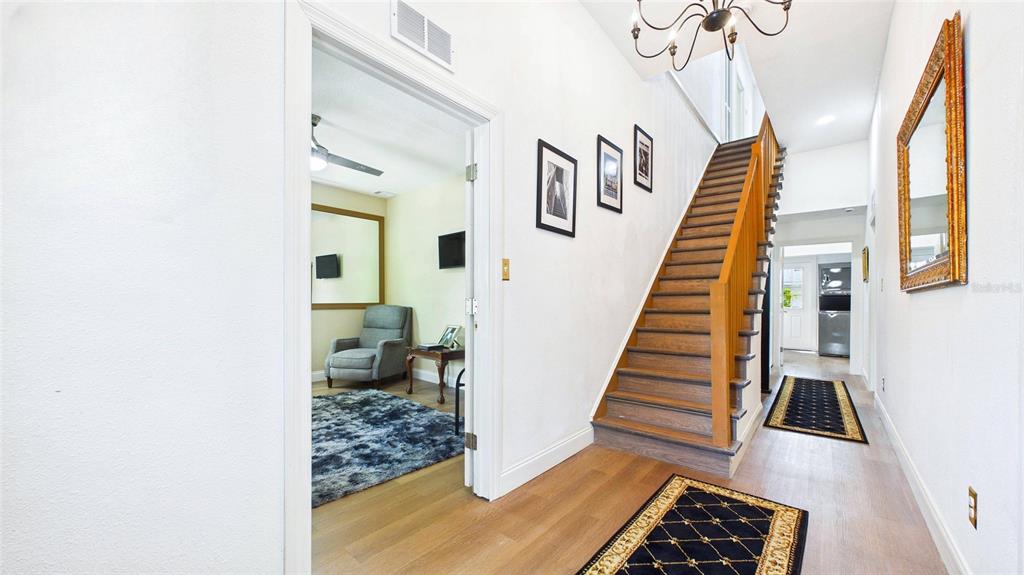 A hallway features light wood flooring, a wooden staircase, and a doorway leading to a room — 2610 W CYPRESS STREET, TAMPA, FL