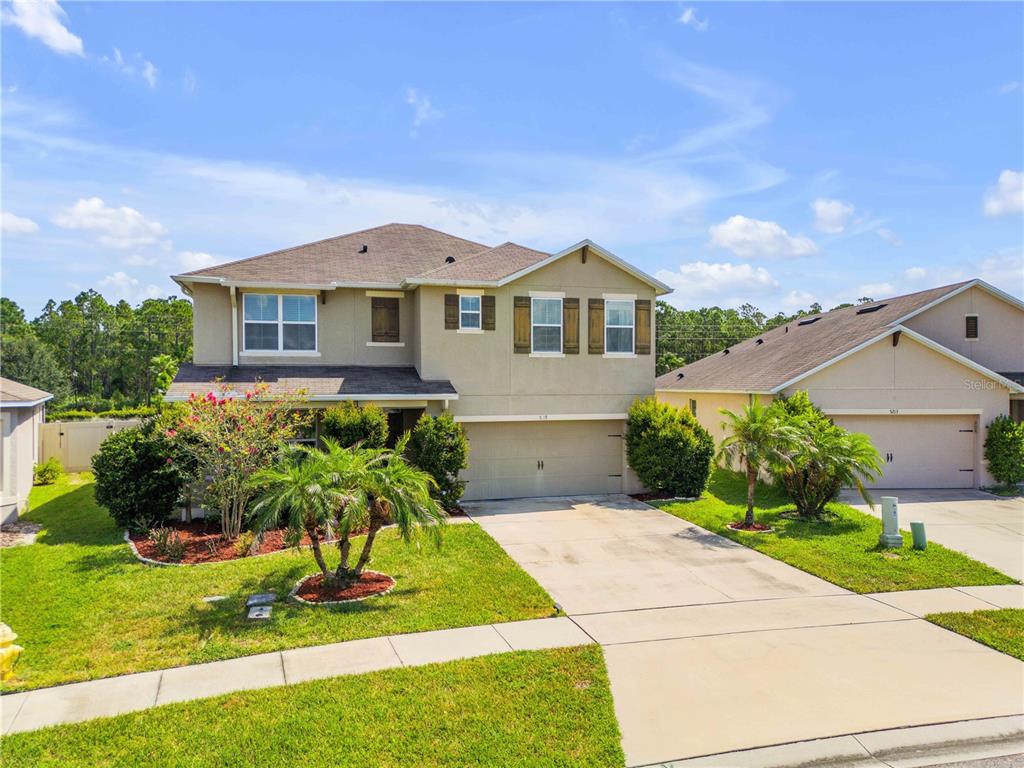 A covered front porch features a wooden bench, potted plants, and a tan front door — 5215 BEAR CORN RUN, PORT ORANGE, FL