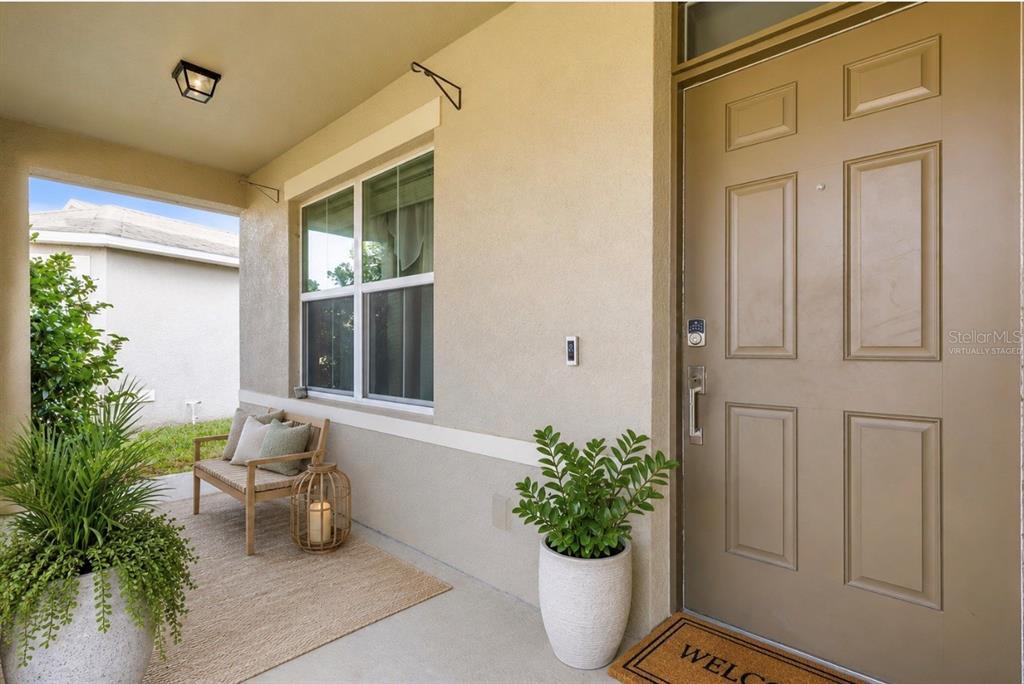 A covered entryway features a tan front door, a window, and a concrete porch floor — 5215 BEAR CORN RUN, PORT ORANGE, FL