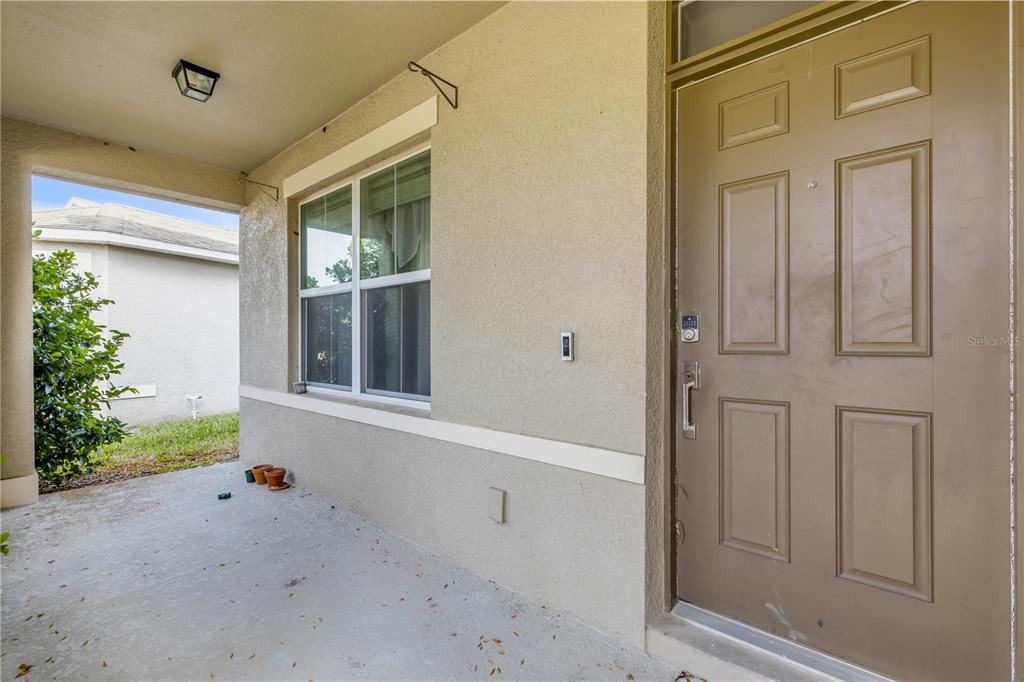 A living room with light wood floors, a white front door, and neutral-toned furniture — 5215 BEAR CORN RUN, PORT ORANGE, FL