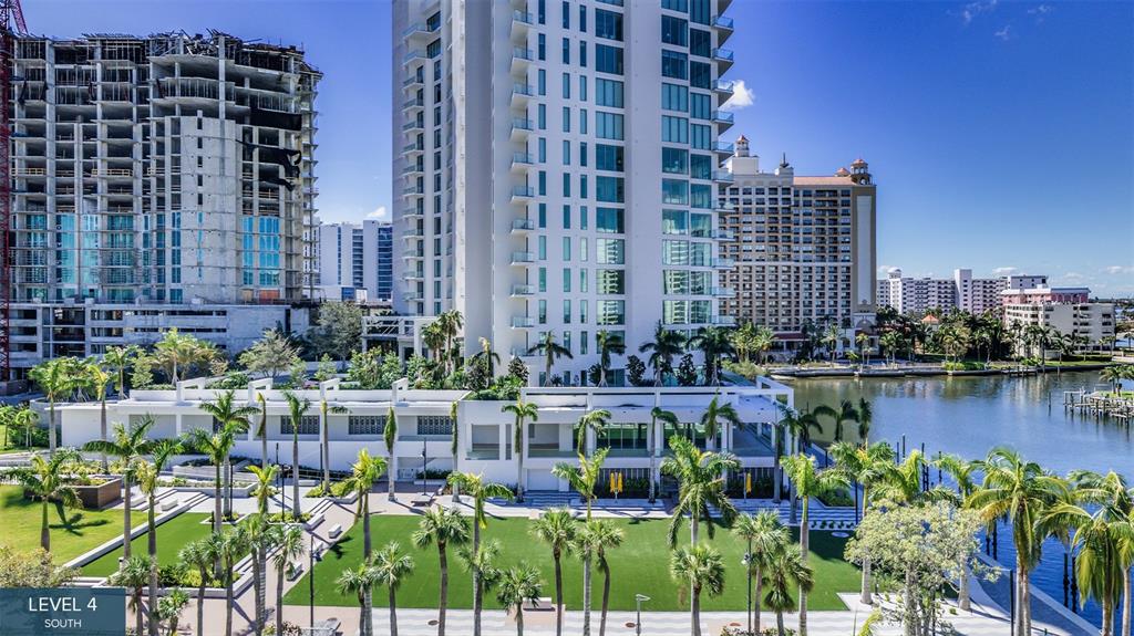 An exterior view of a high-rise building with a landscaped lawn and a waterfront area — 555 QUAY COMMON UNIT 401, SARASOTA, FL
