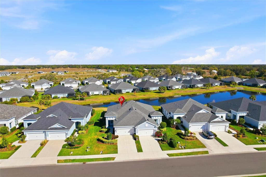 An aerial view shows a suburban neighborhood with several single-family homes and a small pond — 14530 BAREFOOT LANE, PARRISH, FL