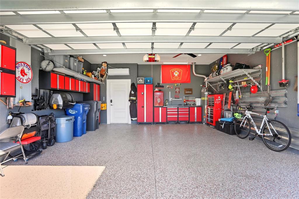 A clean, organized garage features red metal cabinets, a workbench, and a speckled epoxy floor — 14530 BAREFOOT LANE, PARRISH, FL