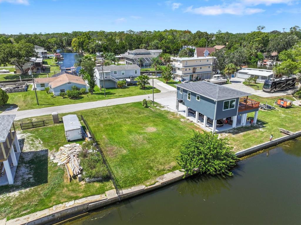 An aerial view shows a waterfront lot with a blue stilt house and a trailer — 6262 ISLAND DRIVE, SPRING HILL, FL