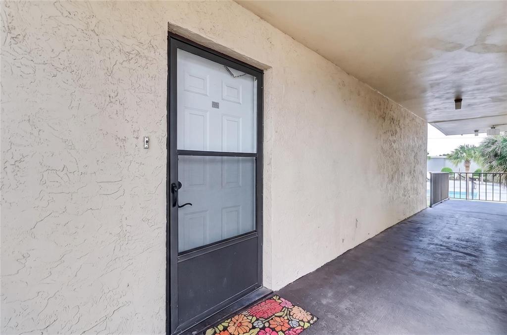 A living room features wood-look flooring, a floral sofa, a glass coffee table, and white walls — 1130 N LAKE PARKER AVENUE UNIT E233, LAKELAND, FL