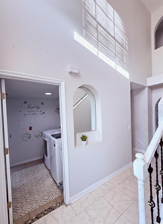 A laundry room with a patterned rug sits beside an arched wall niche and staircase — 5764 ROYAL HILLS CIRCLE, WINTER HAVEN, FL