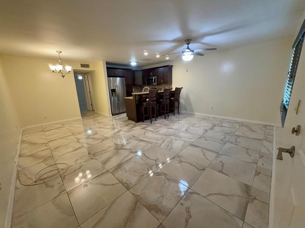 An open-concept kitchen and dining area features dark wood cabinets and large marble-look floor tiles — 9109 W HILLSBOROUGH AVENUE UNIT J109, TAMPA, FL