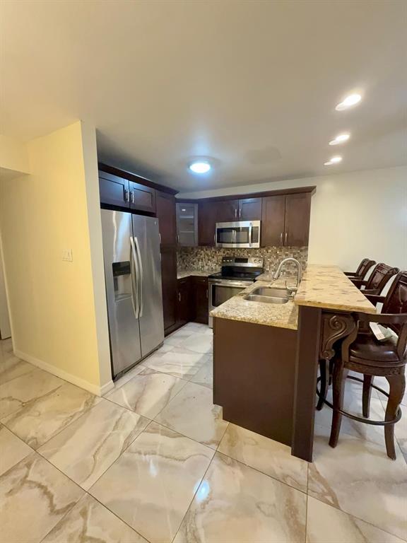 A kitchen features dark wood cabinets, stainless steel appliances, granite countertops, and light-colored tiled floors — 9109 W HILLSBOROUGH AVENUE UNIT J109, TAMPA, FL