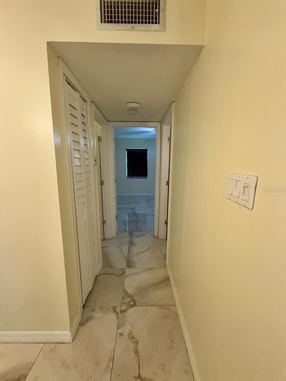 A hallway with light-colored tile flooring leads to a bedroom with a dark window — 9109 W HILLSBOROUGH AVENUE UNIT J109, TAMPA, FL