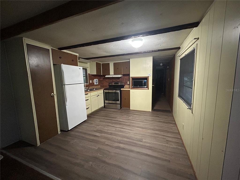 A kitchen features white cabinets, a brick backsplash, stainless steel appliances, and a dining area — 9640 SE 161ST PLACE, SUMMERFIELD, FL