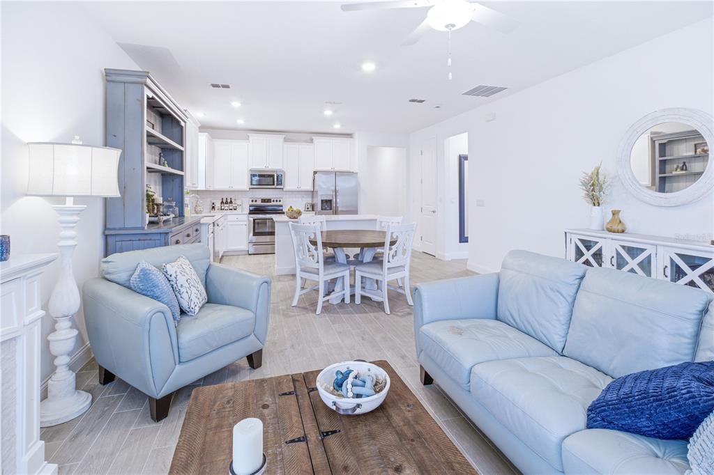 A bright living room and kitchen area features light blue furniture and white cabinetry — 43 TYSON COURT, ST AUGUSTINE, FL
