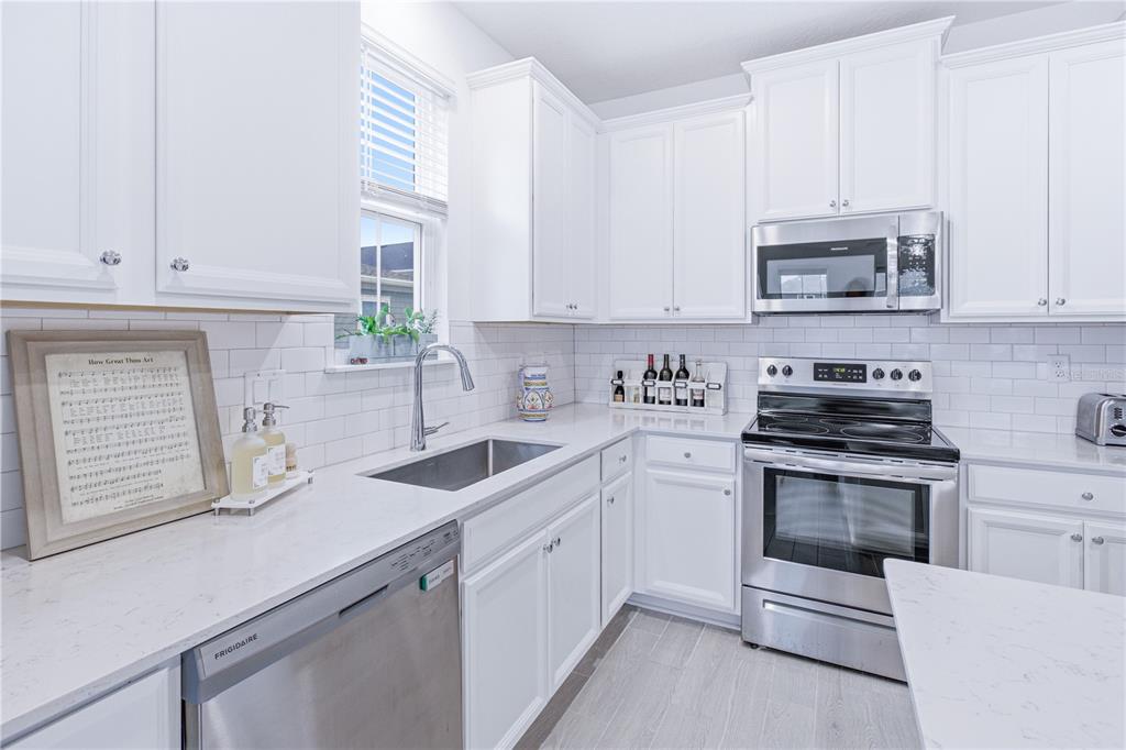 A bright kitchen features white cabinets, stainless steel appliances, and white quartz countertops — 43 TYSON COURT, ST AUGUSTINE, FL