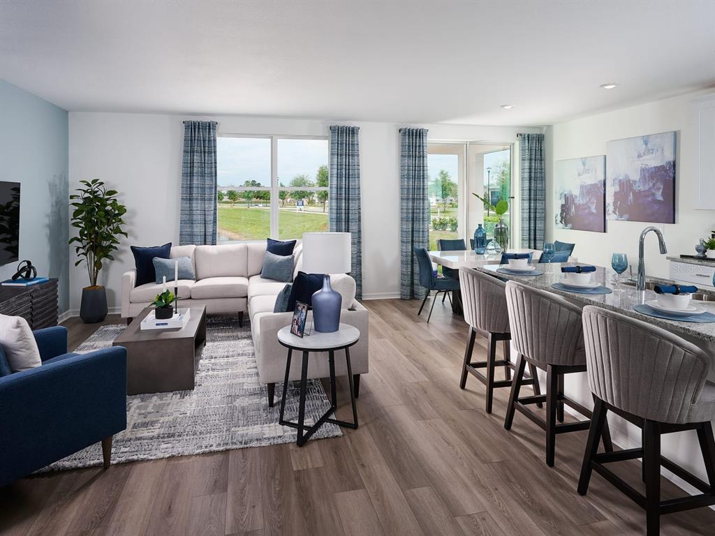 An open-concept living and dining area features wood-look flooring, a sectional sofa, and kitchen island — 833 SILVERADO TRAIL DRIVE, LAKE HAMILTON, FL
