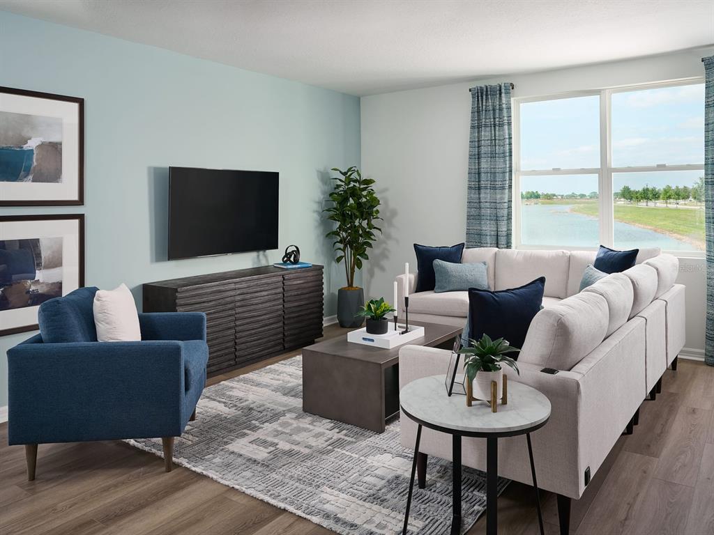 A living room features a blue armchair, a sectional sofa, and a view of water — 833 SILVERADO TRAIL DRIVE, LAKE HAMILTON, FL