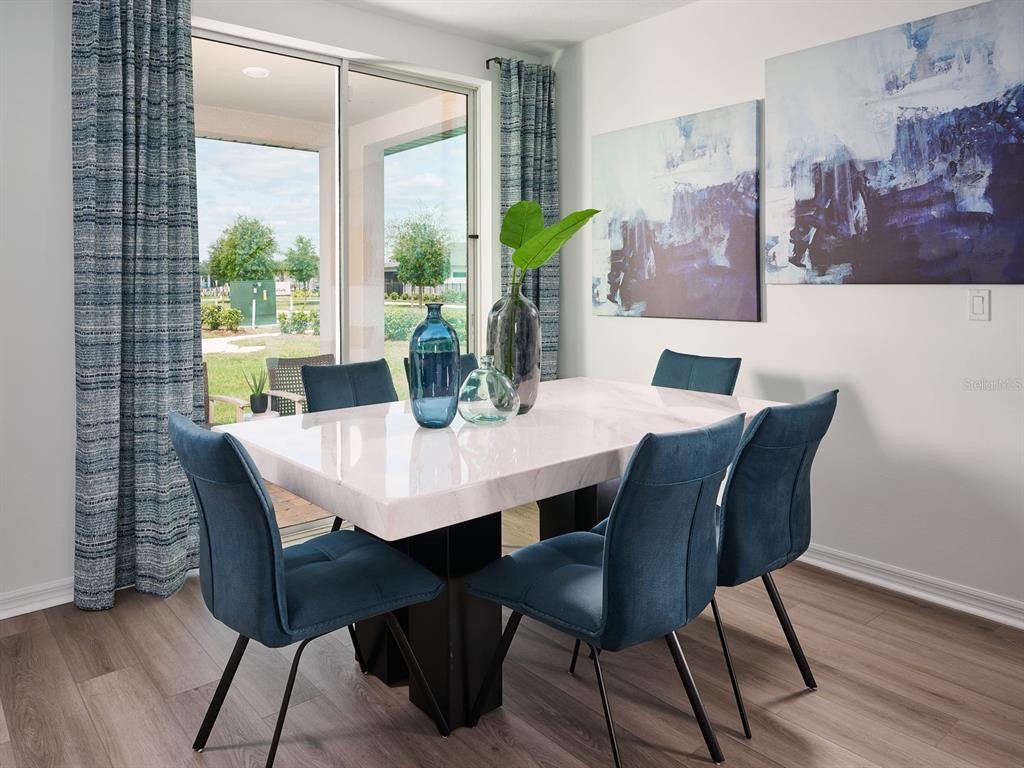 A dining room features a marble-topped table, blue upholstered chairs, and large abstract wall art — 833 SILVERADO TRAIL DRIVE, LAKE HAMILTON, FL