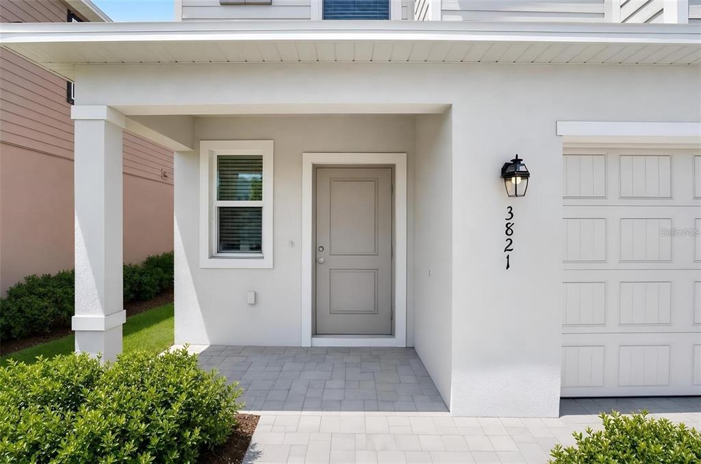 The exterior of a house features a gray front door, a porch, and a garage — 3821 AMBERSWEET CROSSING, PARRISH, FL