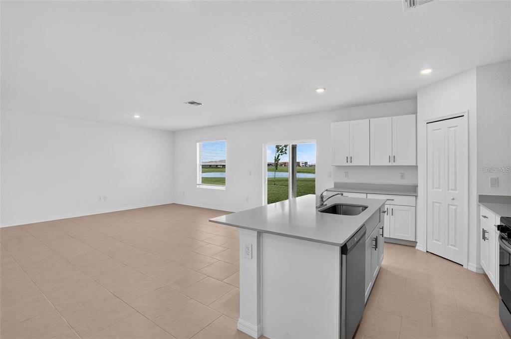 A kitchen with a center island and white cabinets opens into a spacious living area — 3821 AMBERSWEET CROSSING, PARRISH, FL