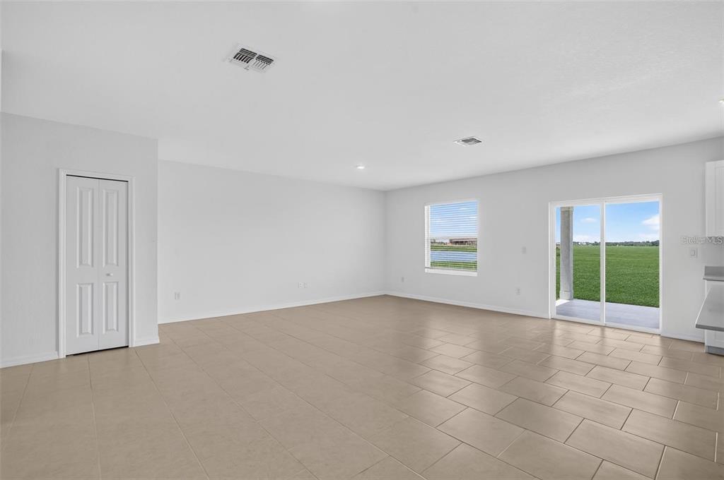 An empty living area features light-colored tile flooring, white walls, a closet, and sliding glass doors — 3821 AMBERSWEET CROSSING, PARRISH, FL