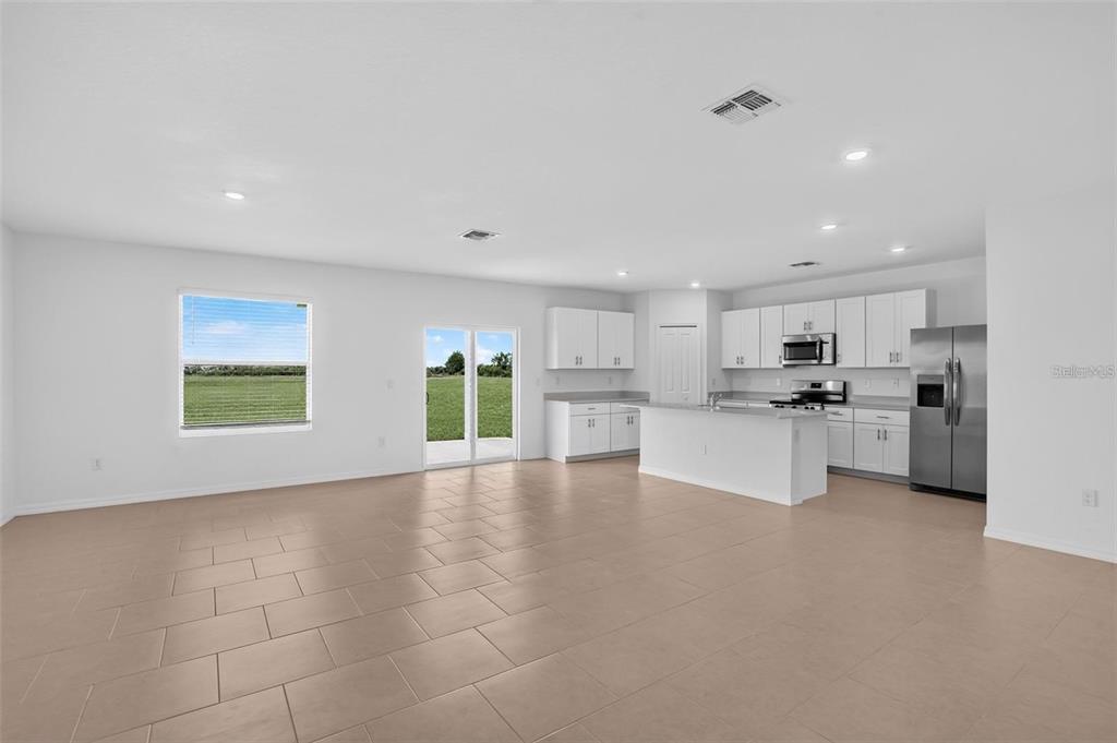An open-concept kitchen and living area features white cabinetry, stainless steel appliances, and tile flooring — 3821 AMBERSWEET CROSSING, PARRISH, FL