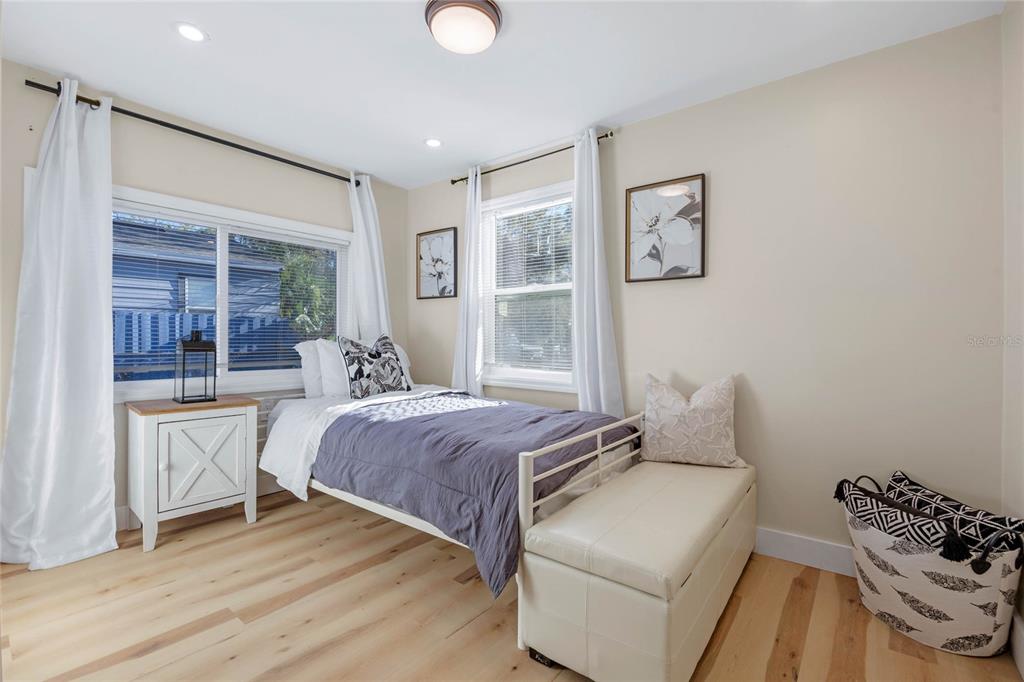 A bedroom features a twin bed, a white storage bench, and light wood flooring — 4809 THORPE AVENUE, ORLANDO, FL