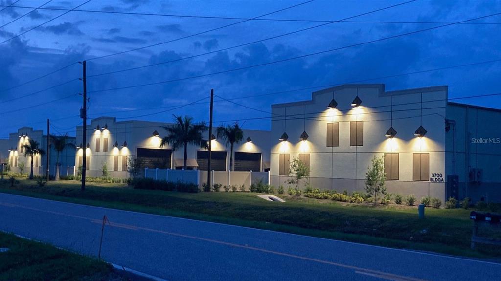 An exterior view of a commercial building complex at dusk with illuminated wall-mounted lights — 5229 TAYLOR ROAD UNIT C3, PUNTA GORDA, FL
