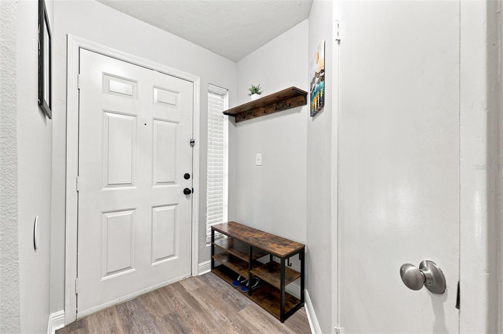 An entryway features a white front door, a wooden shoe rack, and a wall-mounted shelf — 8630 MALLARD RESERVE DRIVE UNIT 203, TAMPA, FL