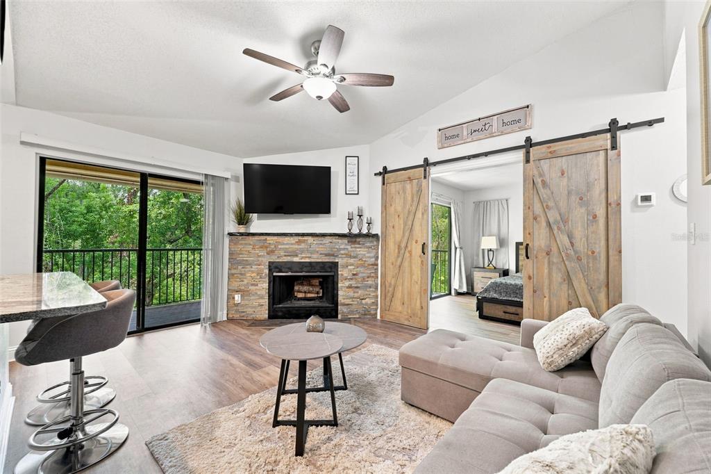 A living room features a stone fireplace, sliding barn doors, and a balcony view — 8630 MALLARD RESERVE DRIVE UNIT 203, TAMPA, FL