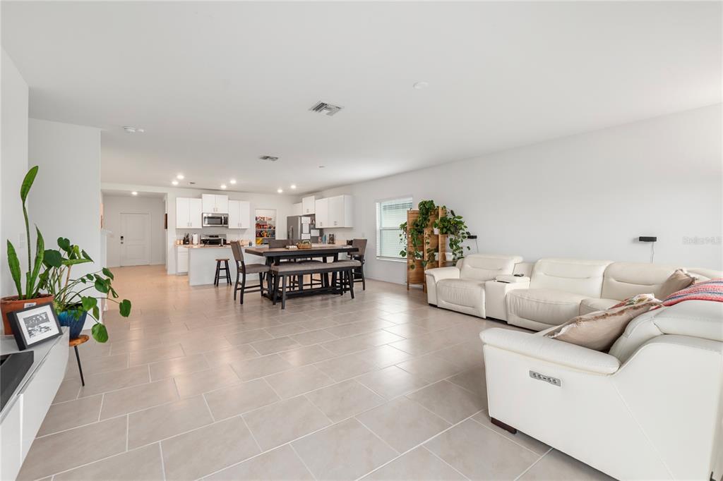 An open-concept living room and kitchen feature white cabinetry, tile flooring, and a dining table — 17177 MONTE ISOLA WAY, NORTH FORT MYERS, FL