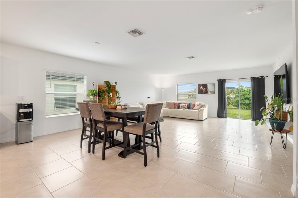 A bright, open-concept living and dining area features tile flooring, a dining set, and a sectional — 17177 MONTE ISOLA WAY, NORTH FORT MYERS, FL
