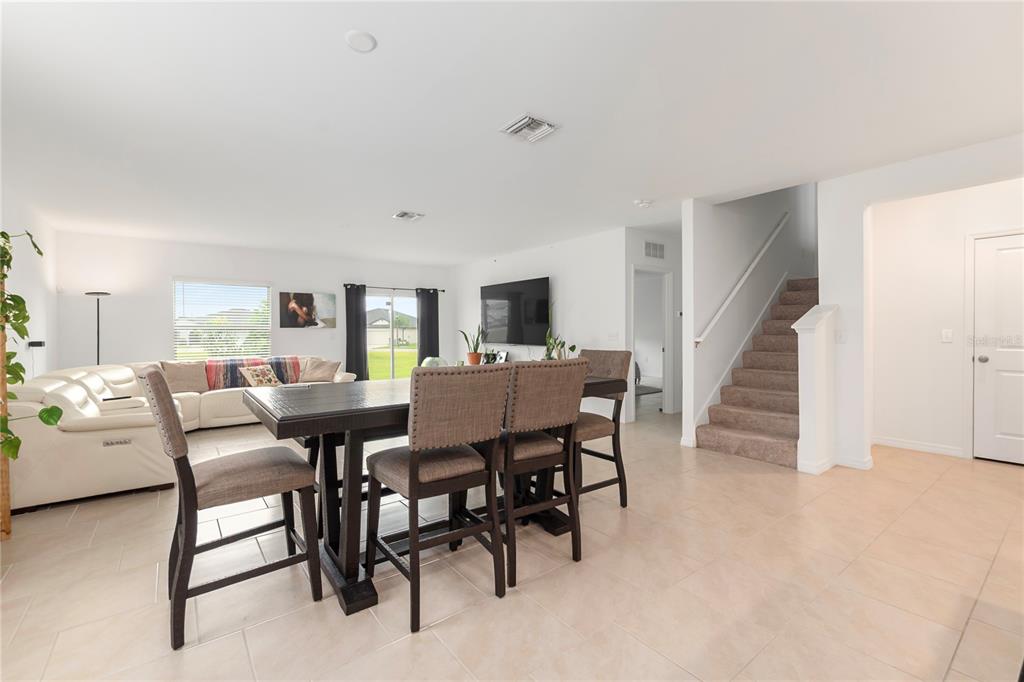 A dining area with a dark wood table and chairs sits before a living room — 17177 MONTE ISOLA WAY, NORTH FORT MYERS, FL