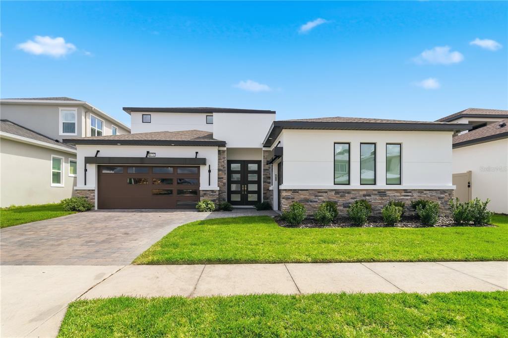A modern one-story house with a stone facade, a brown garage door, and a paved driveway — 10782 TORCHWOOD SEA WAY, SAN ANTONIO, FL