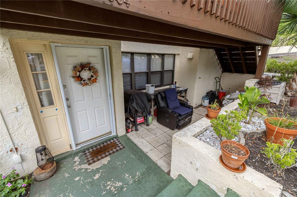 An exterior view shows a white front door, a patio area, and a raised garden bed — 964 5TH STREET UNIT 964, CLERMONT, FL