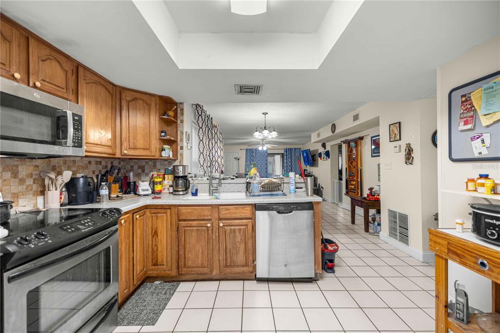 A kitchen with wood cabinets, tiled floors, and a stainless steel dishwasher and microwave — 964 5TH STREET UNIT 964, CLERMONT, FL