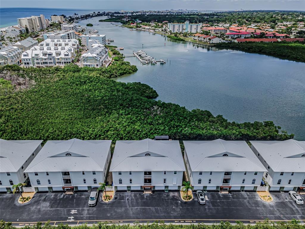 An exterior view of a multi-story residential building with white siding and garage doors — 19829 GULF BOULEVARD UNIT 501, INDIAN SHORES, FL