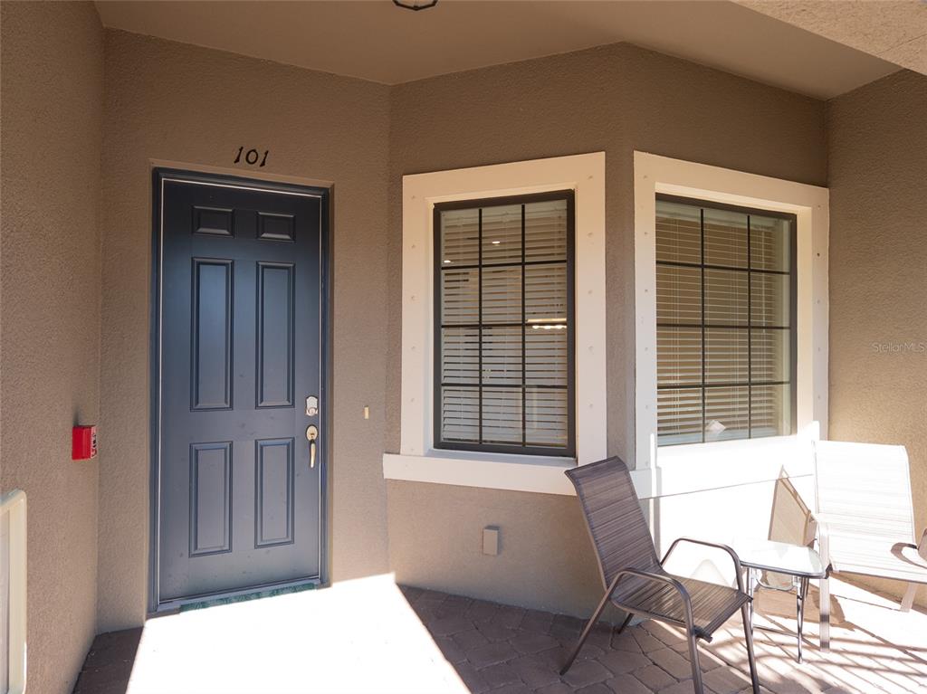 A dark blue front door with the number 101 sits beside two windows and patio furniture — 12405 OSORIO COURT UNIT 101, SARASOTA, FL
