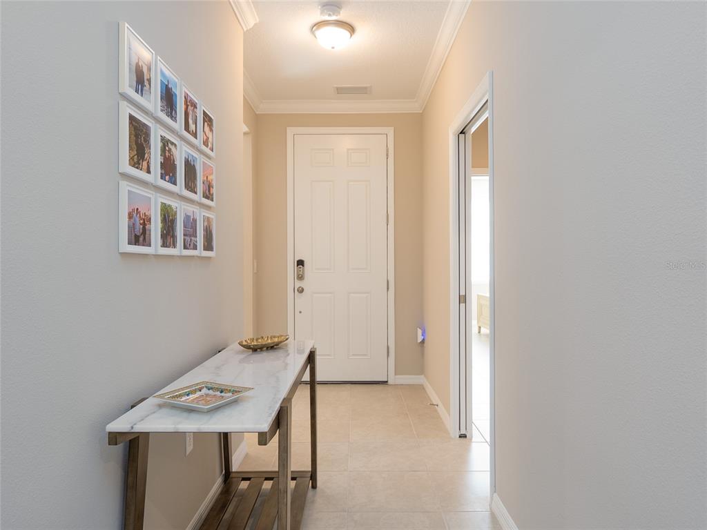 A hallway features a marble-topped console table, a photo gallery wall, and a white door — 12405 OSORIO COURT UNIT 101, SARASOTA, FL