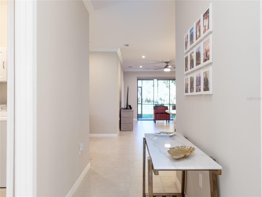 A hallway with a marble-topped console table leads to an open living area with tile flooring — 12405 OSORIO COURT UNIT 101, SARASOTA, FL