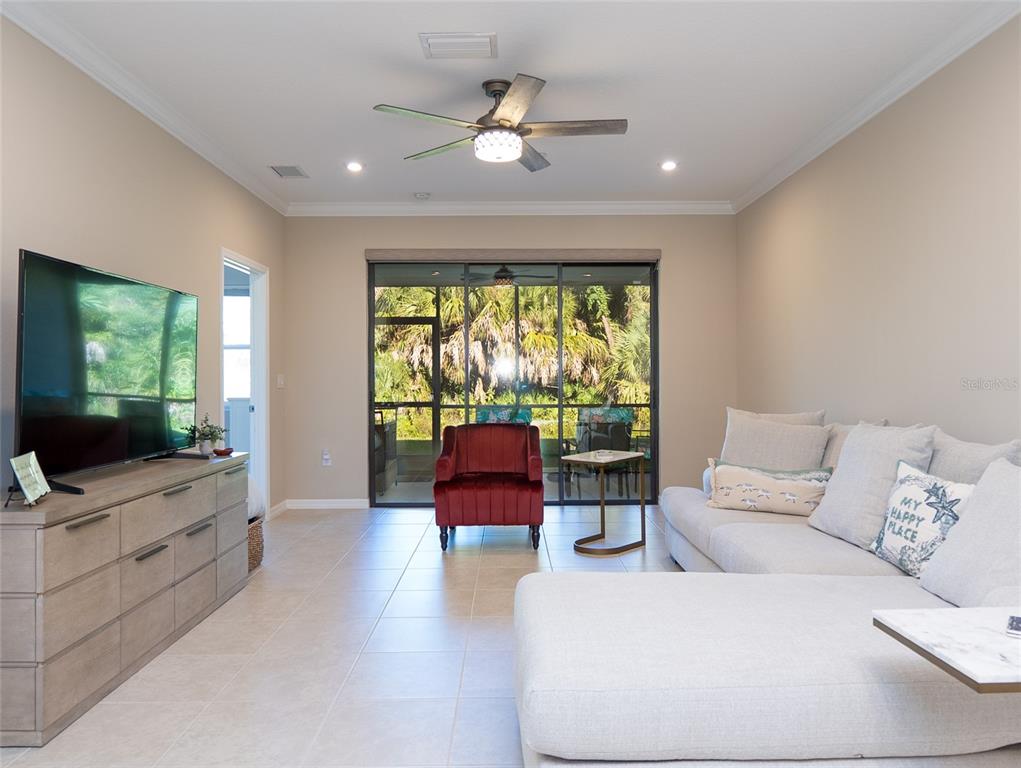 A living room features a large sectional sofa, a red armchair, and a sliding glass door — 12405 OSORIO COURT UNIT 101, SARASOTA, FL
