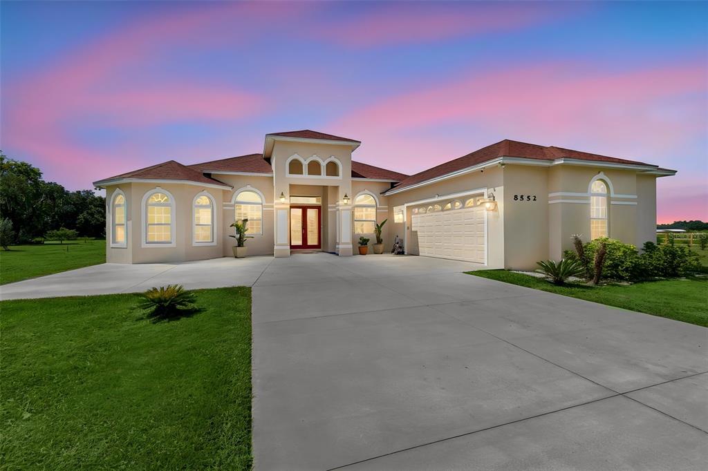 A single-story house with a beige stucco exterior, red roof, and a large concrete driveway — 8552 BRANDING IRON TRAIL, PLANT CITY, FL
