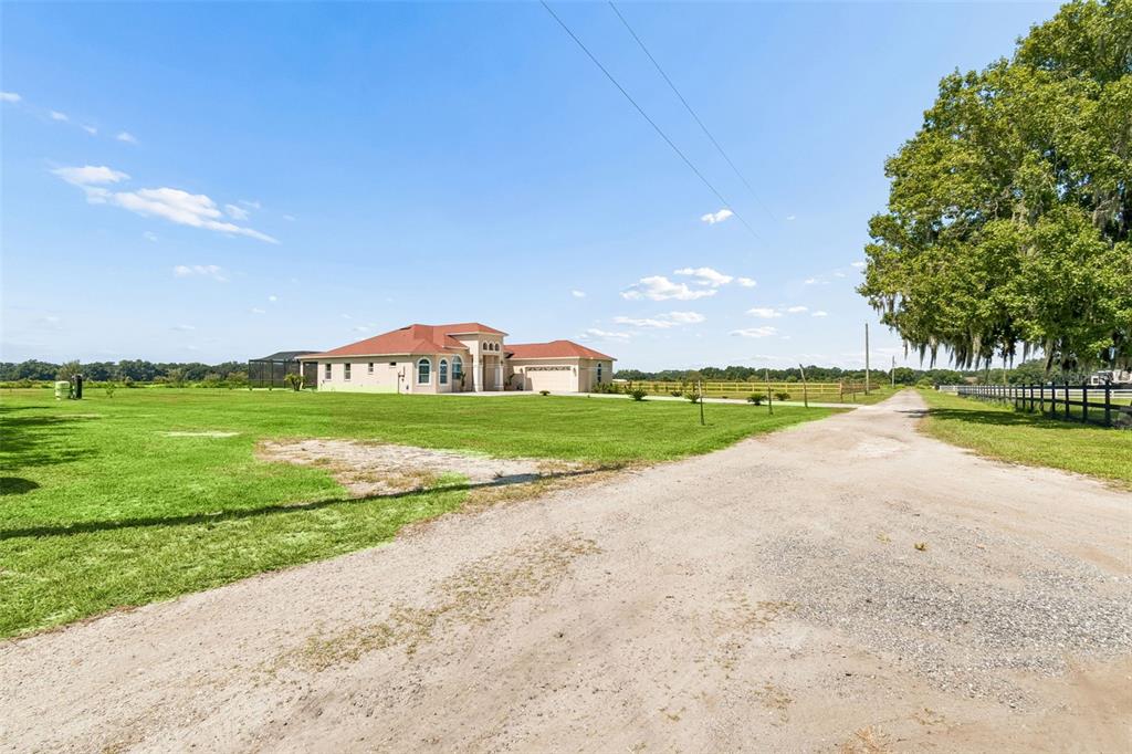 A modern white kitchen features a large granite island, stainless steel appliances, and tile flooring — 8552 BRANDING IRON TRAIL, PLANT CITY, FL