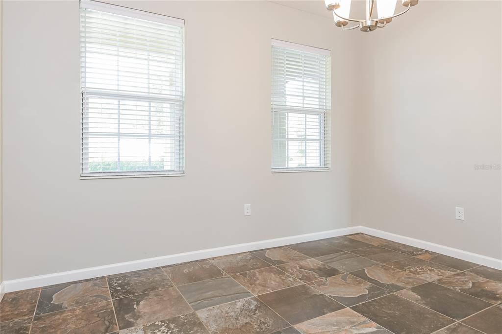 A dining room with two windows, a chandelier, and brown slate-style tile flooring — 2270 NATOMA BOULEVARD, MOUNT DORA, FL