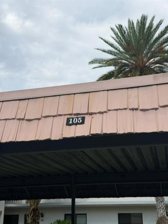 A covered parking space features a light-colored shingled roof with the number 105 displayed — 105 LAKEVIEW WAY UNIT 105, OLDSMAR, FL