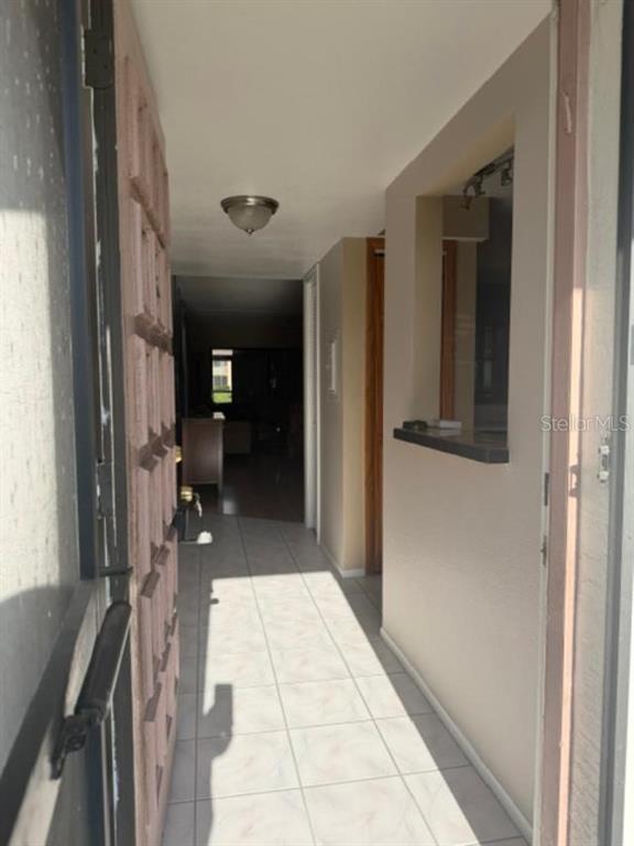 An entryway with light-colored tile flooring leads into a home interior with a pass-through window — 105 LAKEVIEW WAY UNIT 105, OLDSMAR, FL